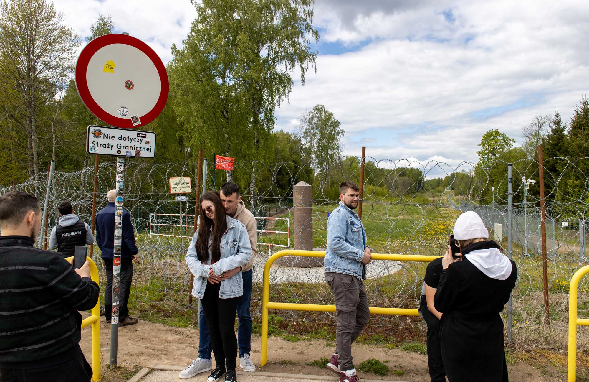 Un grupo de polacos se hacen fotos en la triple frontera entre Polonia, Lituania y Rusia, con la bandera de la hoz y el martillo en el lado ruso