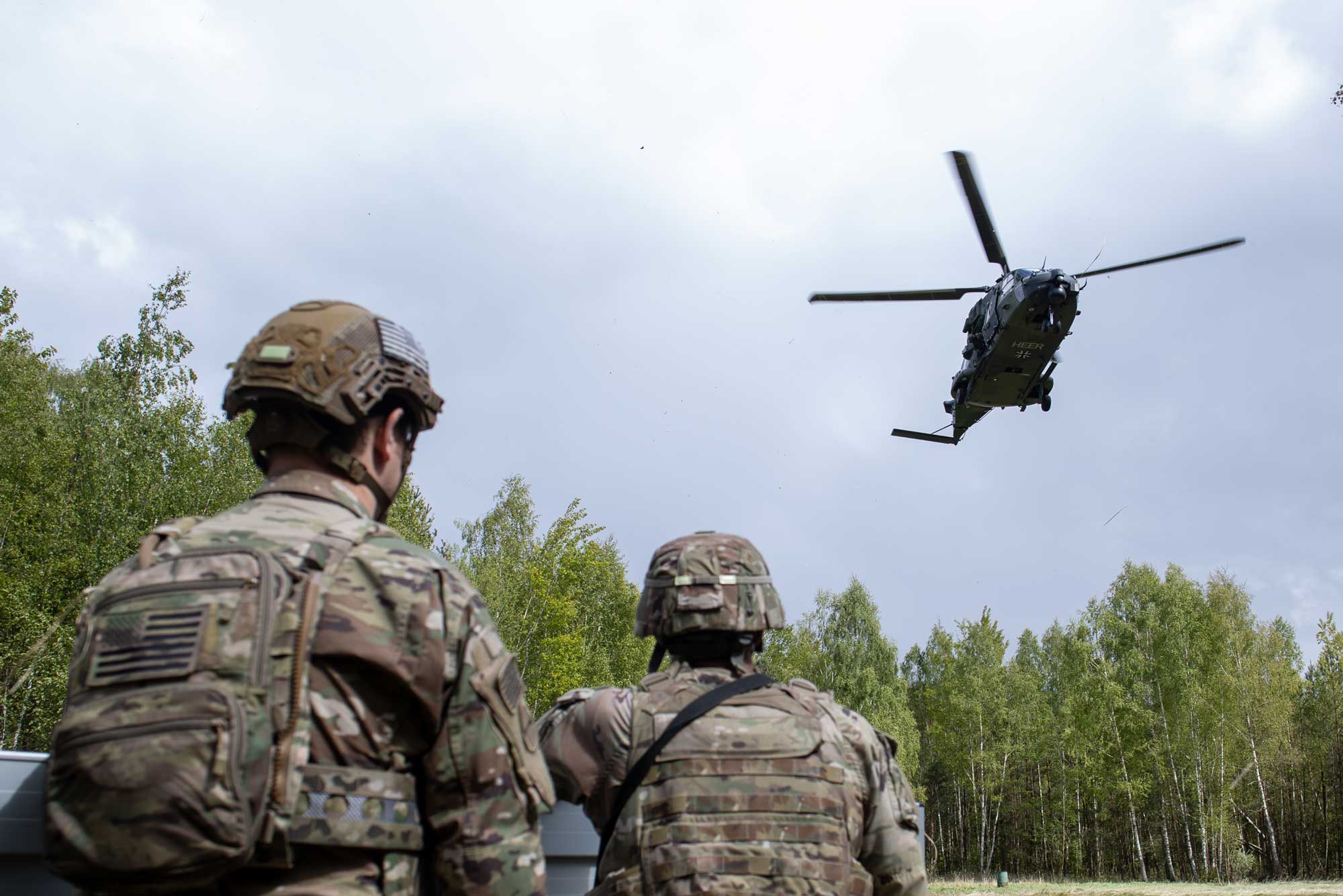 Dos soldados americanos observan el aterrizaje de un helicóptero alemán NH90