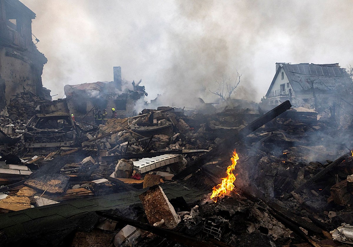 Residentes limpian los escombros en el lugar donde se encuentra un edificio residencial de nueve plantas alcanzado por un avión no tripulado en Kiev