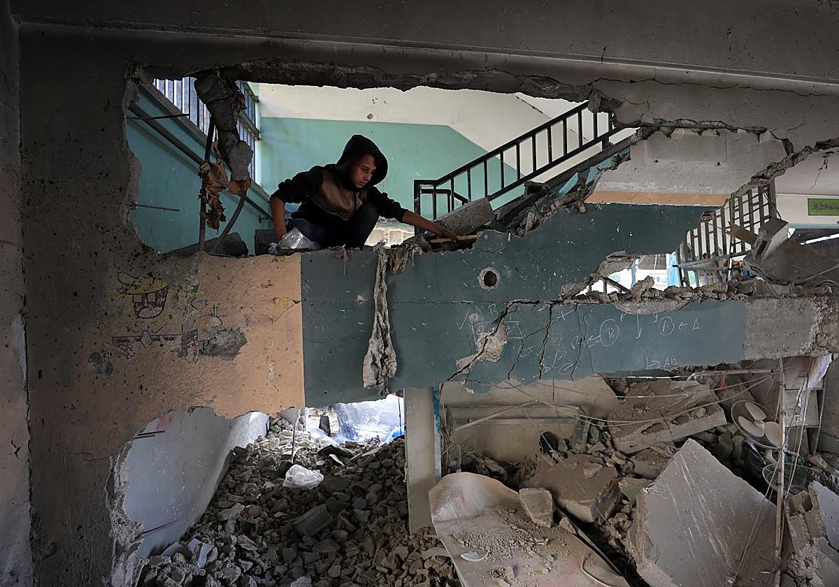 Un palestino inspecciona los daños de la escuela utilizada como refugio