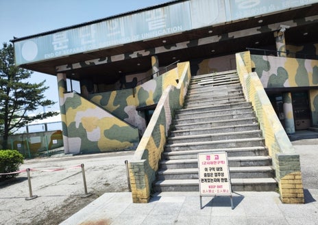 Imagen secundaria 1 - Turistas chinos se fotografían en las instalaciones del parque de Imjingak, frente a la ZDC; debajo a la izquierda, un refugio en desuso clama por la unificación; a la derecha, vallas y alambre de espino delimitan la zona bajo control militar