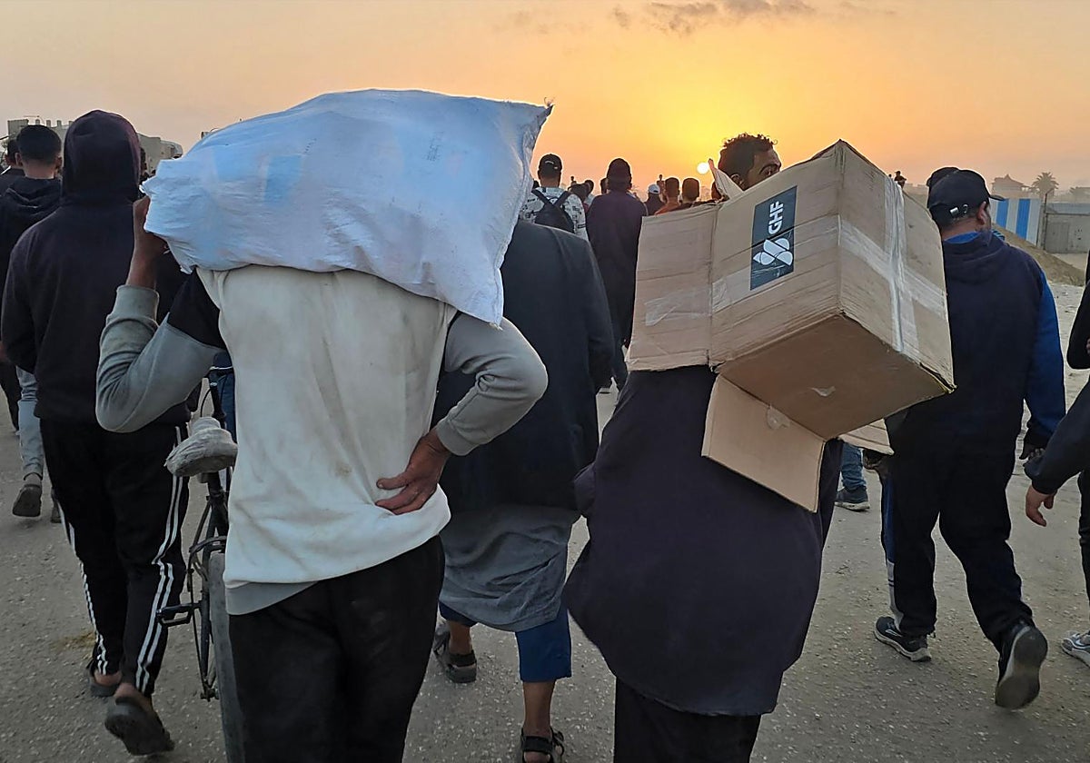 Un joven lleva una caja vacía de suministros de ayuda humanitaria de la Fundación Humanitaria de Gaza (GHF)