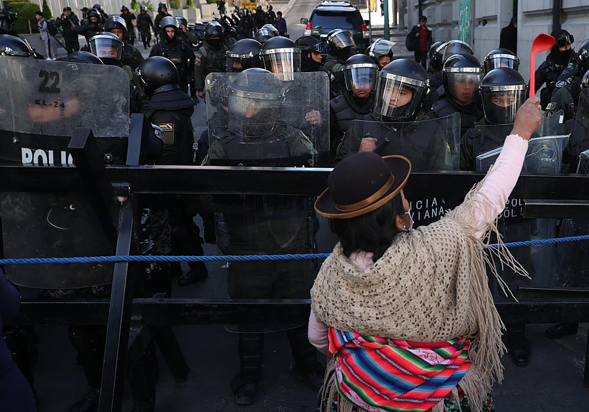 Una mujer aimara protesta contra el presidente de Bolivia, Luis Arce, frente a agentes de policía antidisturbios en La Paz