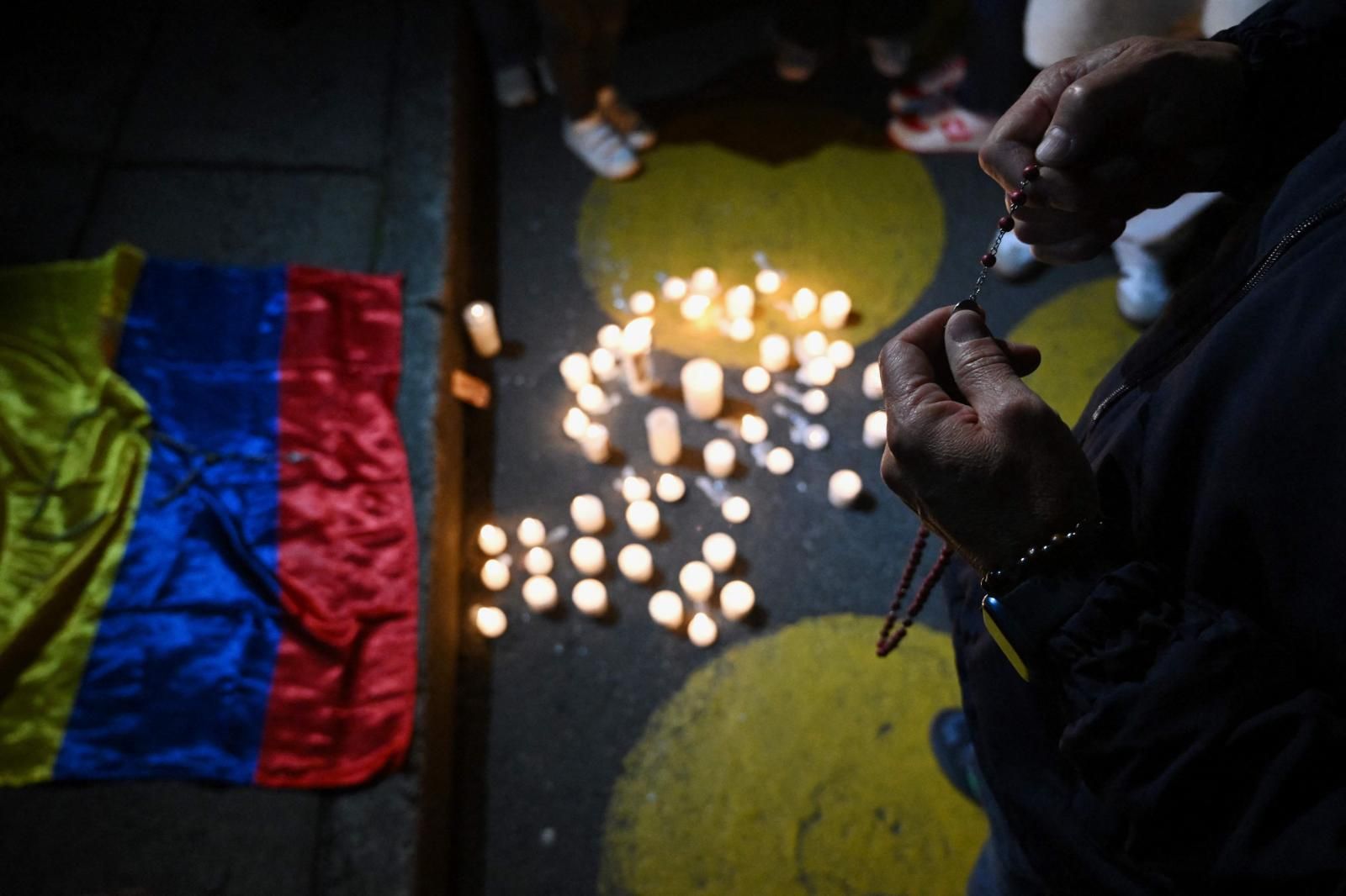 Un hombre sostiene un crucifijo mientras reza frente a la Clínica Fundación Santa Fe, donde el senador Miguel Uribe recibe tratamiento médico tras ser herido de bala en Bogotá.