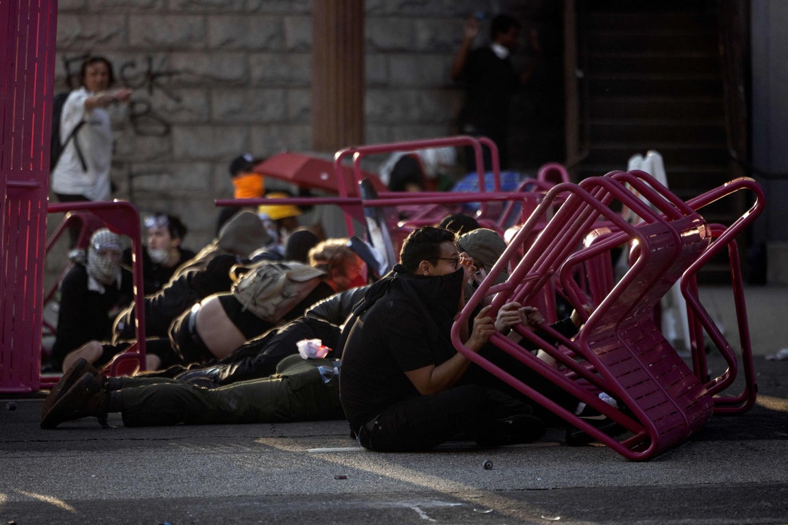 Varios activistas se protegen de la policía con sillas.