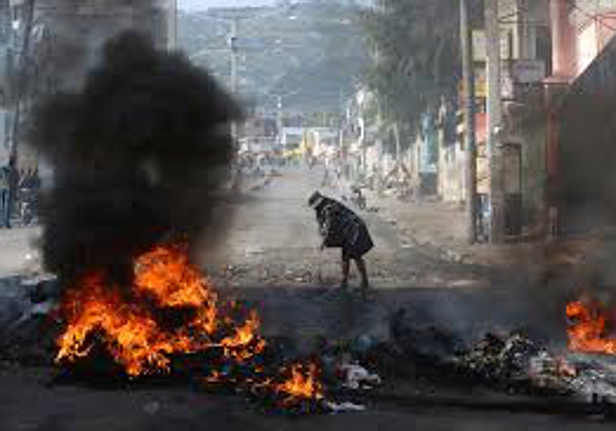 Una mujer pasa junto a una barricada en llamas colocada durante una protesta contra la inseguridad, en el barrio de Petion-Ville de Puerto Príncipe