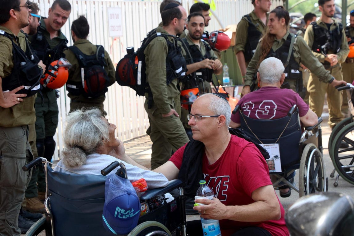 Un hombre atiende a una anciana evacuada de una residencia  por las fuerzas de seguridad cerca del lugar de un ataque iraní en Ness Ziona, en el centro de Israel