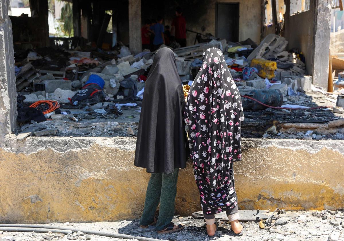 Dos mujeres observan los restos de la escuela Mustafa Hafez, en Gaza, tras los ataques de Israel