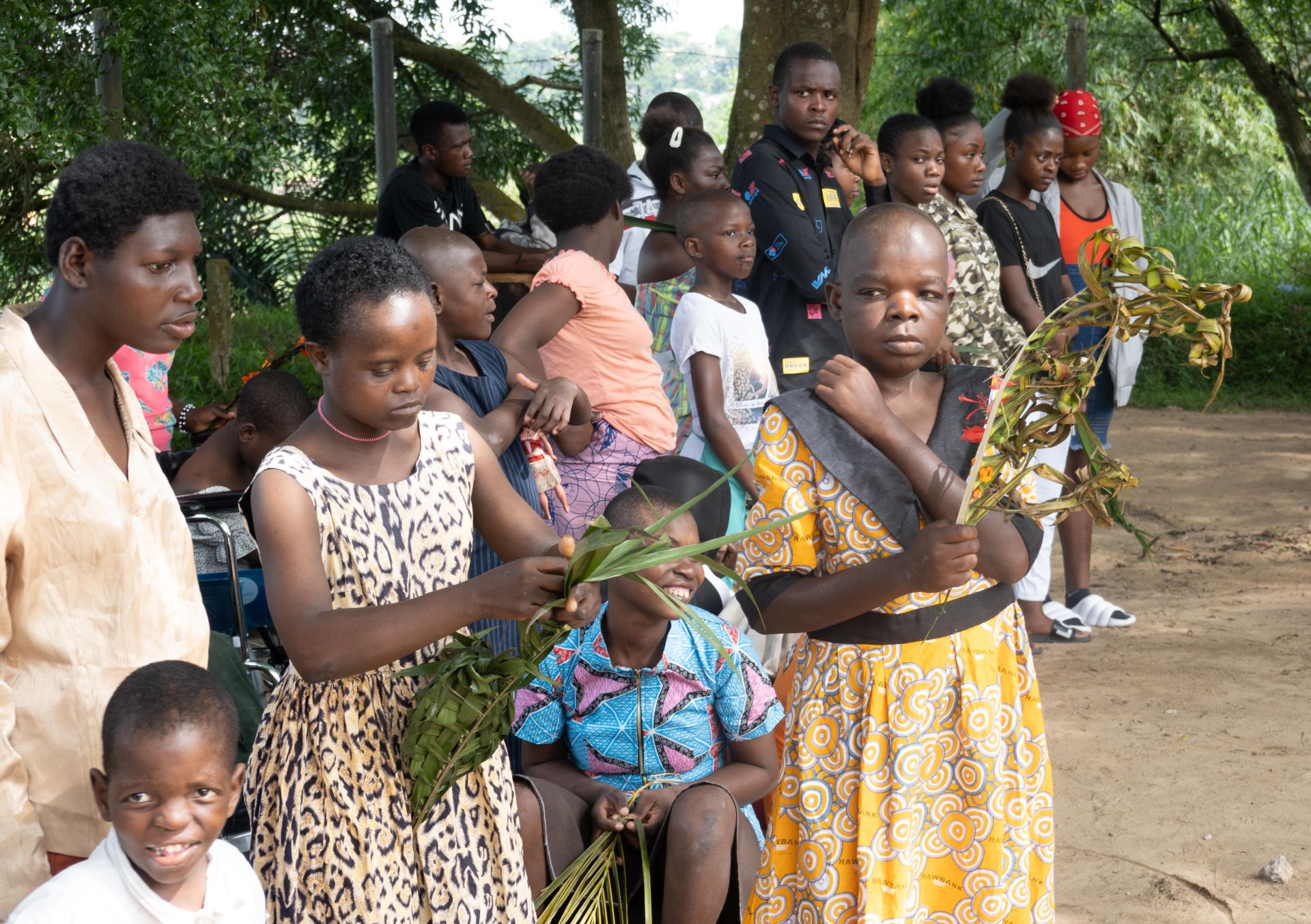 Varios niños y cuidadores esperan el inicio de la ceremonia del Domingo de Ramos en Mama Koko