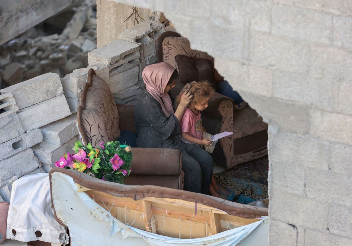 Una mujer peina a una niña entre los escombros de Gaza