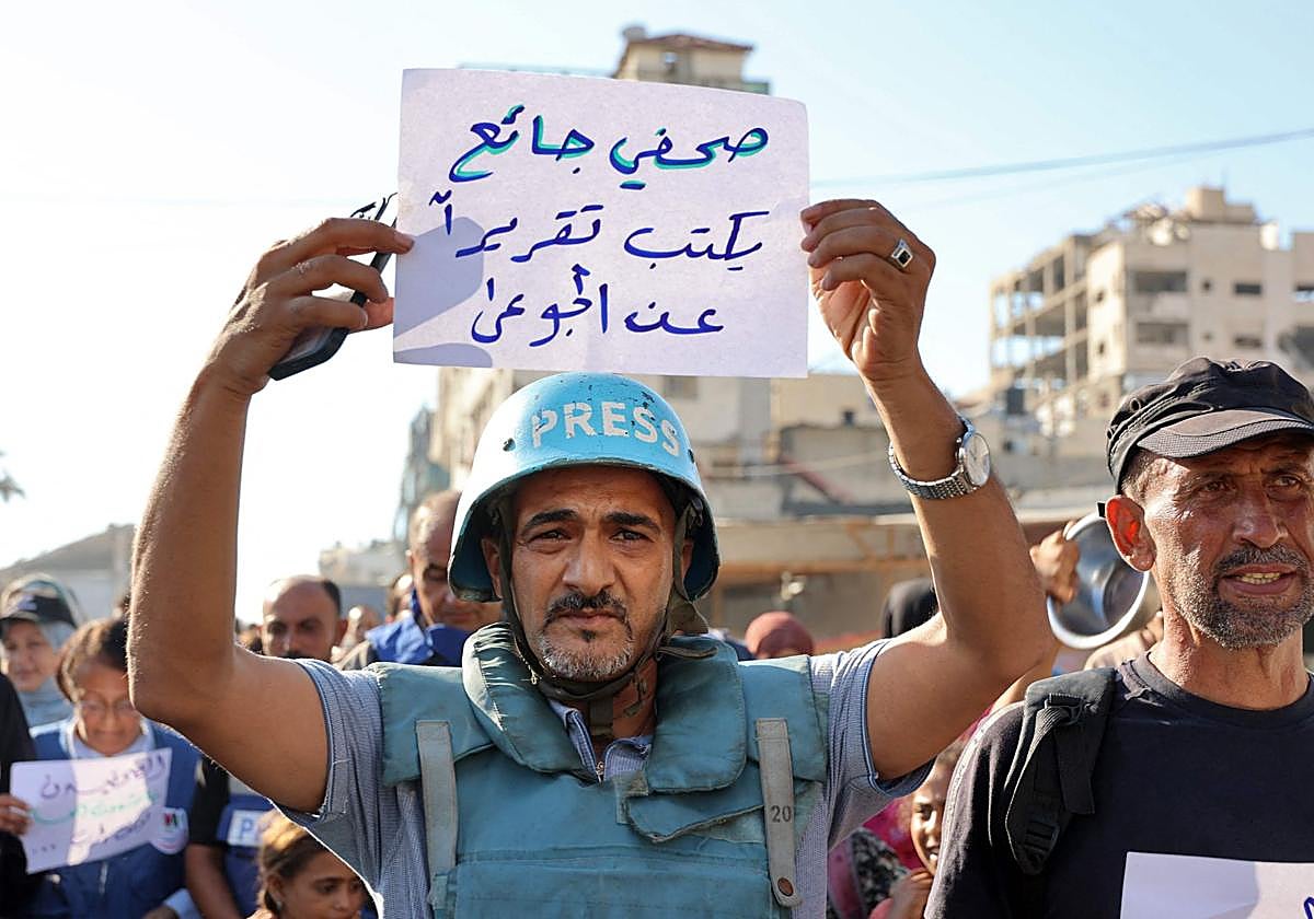 Un manifestante sostiene un cartel en una protesta contra el hambre en Ciudad de Gaza: «Un periodista hambriento escribe un reportaje sobre los hambrientos»