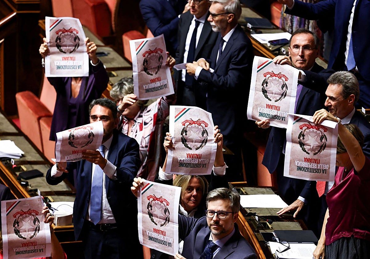 Senadores del opositor Partido Democrático (PD) sostienen hojas de papel con una imagen de la Constitución italiana al revés, durante una votación sobre un proyecto de ley de reforma judicial en el Senado