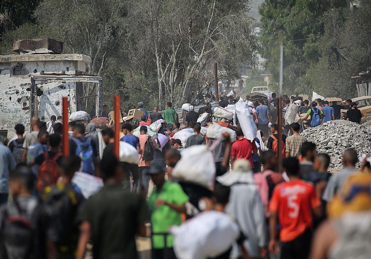 Palestinos desplazados cargan paquetes de ayuda humanitaria.