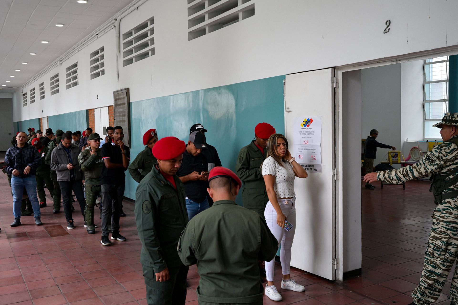 Una fila de votantes, entre los que destacan numerosos militares, hace cola en un colegio electoral de Caracas