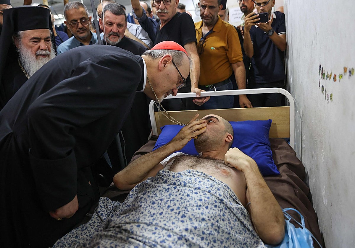 El Patriarca Latino de Jerusalén, Pierbattista Pizzaballa, consuela a un hombre herido en un ataque israelí contra la Iglesia de la Sagrada Familia en julio