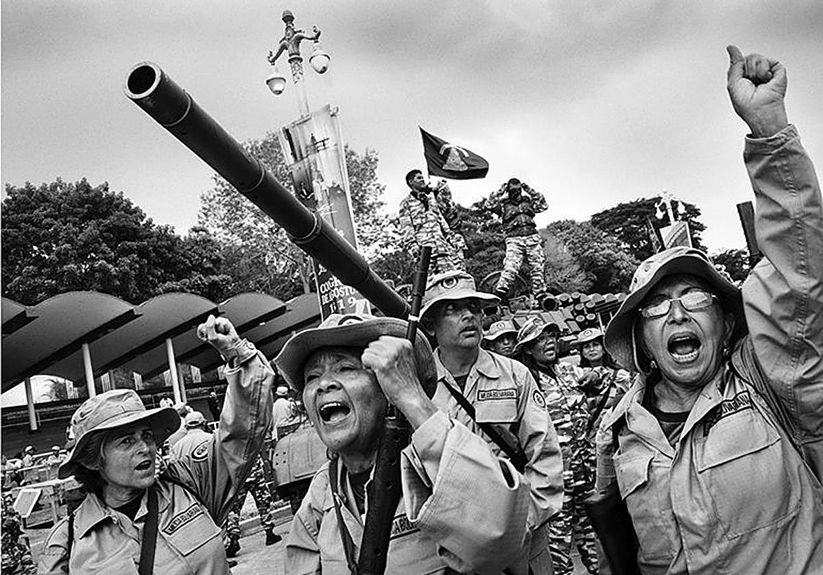 Mujeres milicianas levantan los puños y gritan consignas al paso de un tanque. Sus rostros, encendidos por la consigna revolucionaria, contrastan con la torpeza de los movimientos