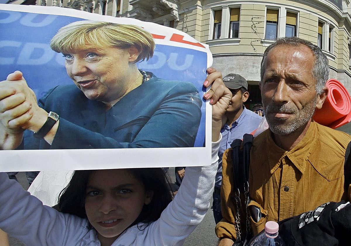 Desde Budapest, una niña inmigrante sostiene un cartel con la imagen de la entonces canciller alemana, Angela Merkel