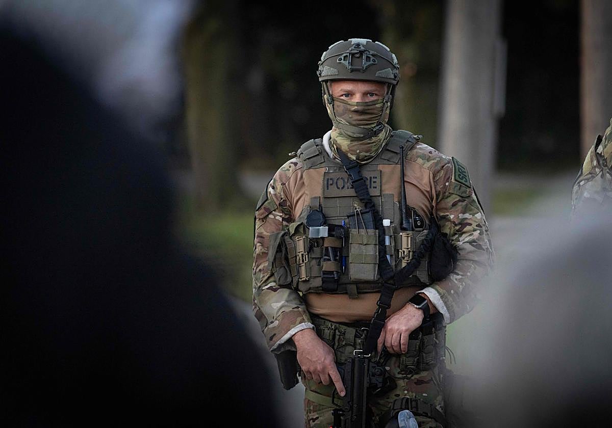 Agentes de la policía federal se encuentran afuera de un centro de procesamiento de inmigración mientras los manifestantes protestan