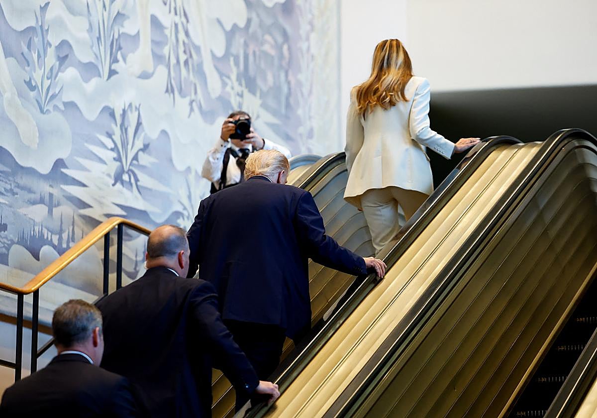 Trump y su esposa suben a pie la escalera mecánica tras el incidente.
