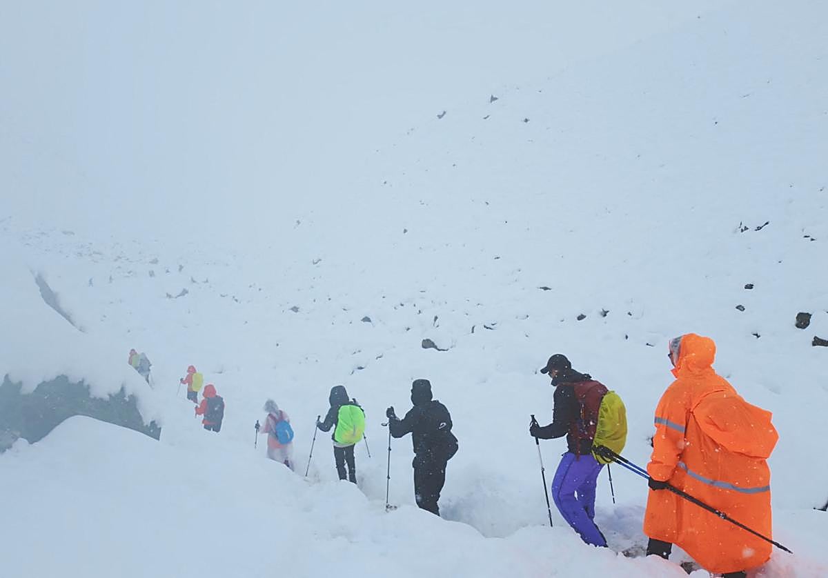Tursitas caminan por el Everest en plena nieve.