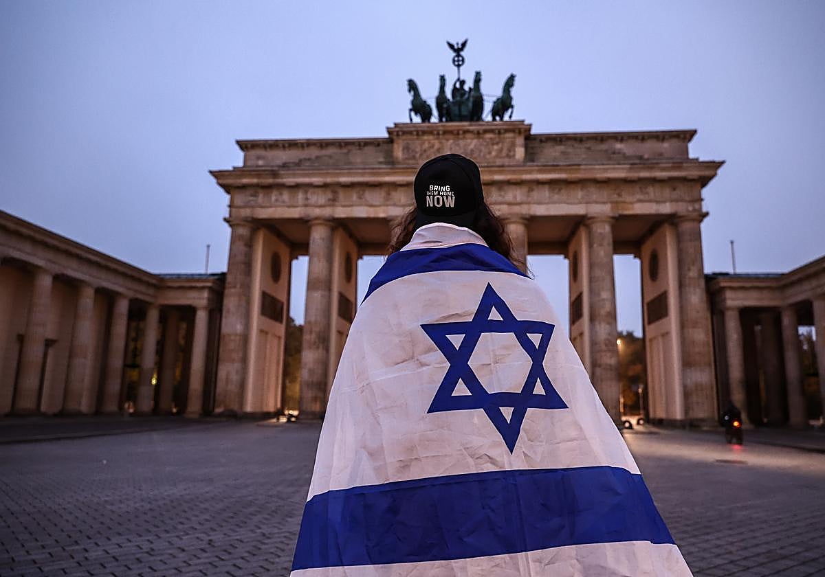 Una mujer lleva una bandera de Israel en homenaje a las víctimas del 7-O en la puerta de Brandenburgo (Berlín)