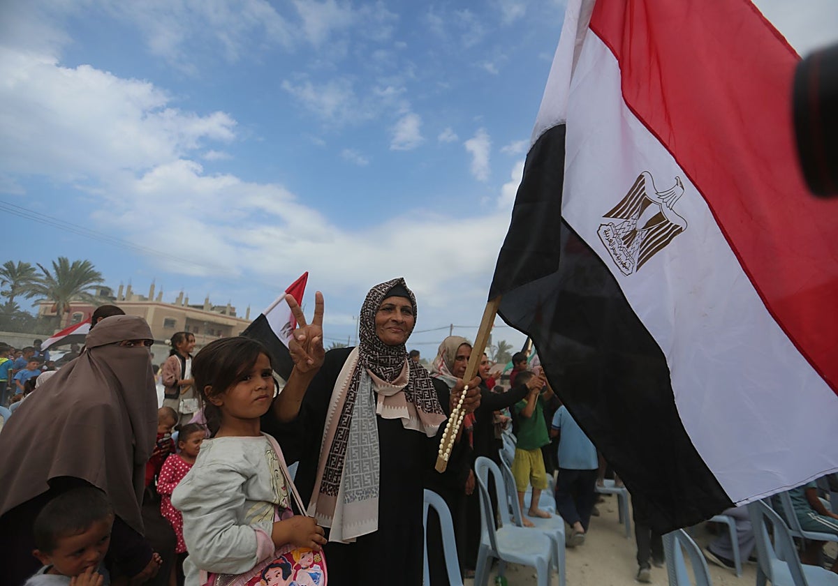Palestinos desplazados ondean banderas egipcias y palestinas mientras celebran