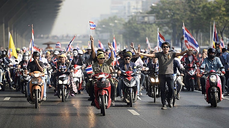 Manifestantes antigubernamentales con banderas nacionales tailandesas conducen sus motocicletas mientras se manifiestan en una calle principal de Bangkok