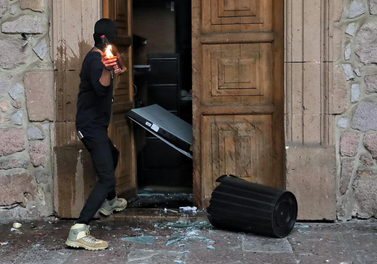 Un manifestante causa destrozos durante una manifestación este domingo, en el Palacio de Gobierno en Morelia (México)
