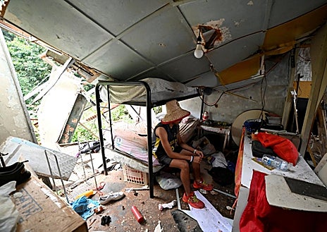 Imagen secundaria 1 - Arriba, la gente carga sus teléfonos tras un apagón en su barrio después de que Estados Unidos atacara Venezuela y capturara a Maduro; debajo a la izquierda, un hombre rescata pertenencias de entre los escombros después del ataque; a la derecha, se puede apreciar cierta normalidad en las calles de Caracas