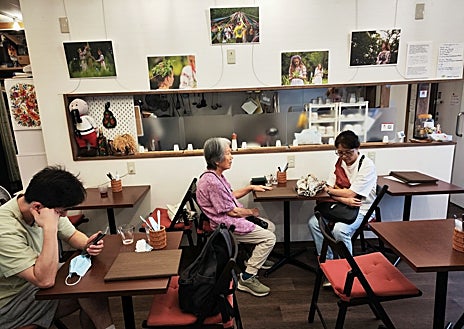 Imagen secundaria 1 - Arriba, Igor Ievtushuk, vicepresidente de la ONG Kraiany, que agrupa a la comunidad ucraniana en Japón. Abajo a la izquierda, los vecinos japoneses del barrio residencial de Nishikubo toman algo en el Café Kraiany. A la derecha, la carta del Café Kraiany ofrece comida típica ucraniana.