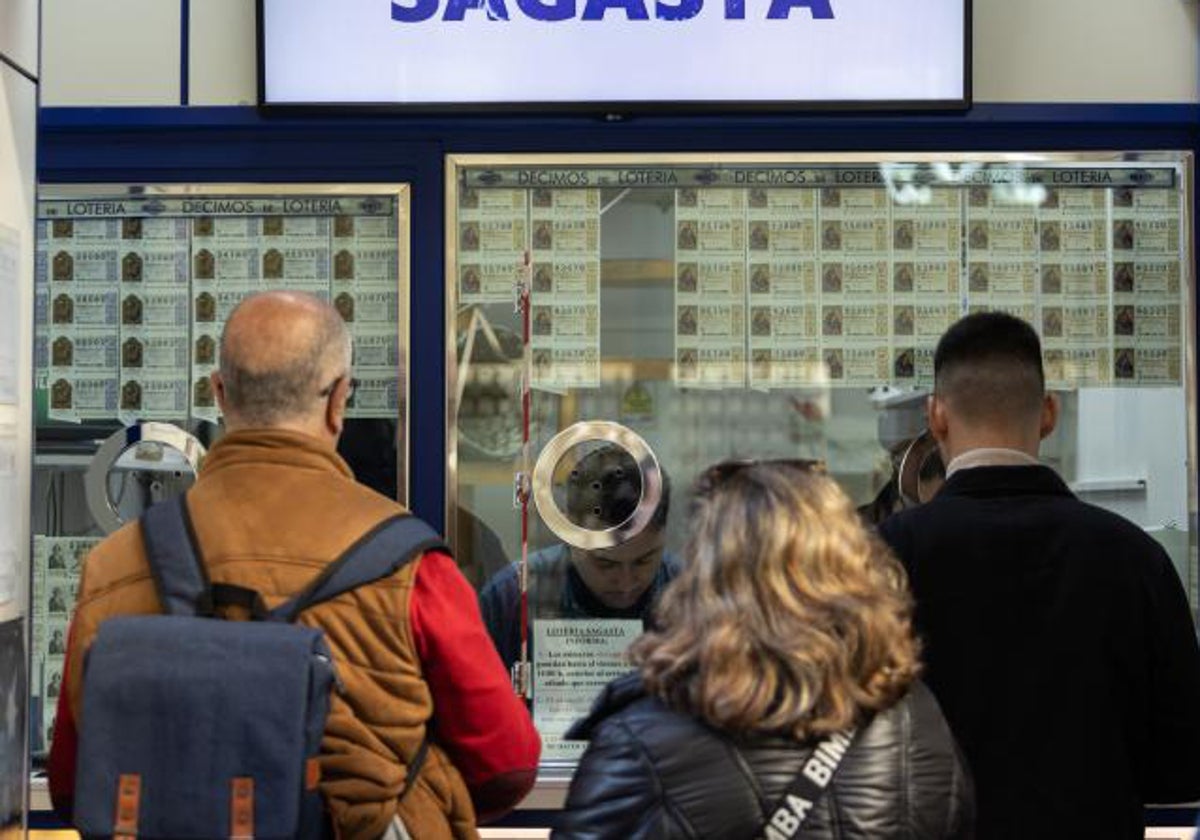 Varias personas, haciendo cola antes de comprar un décimo en una administración de Madrid