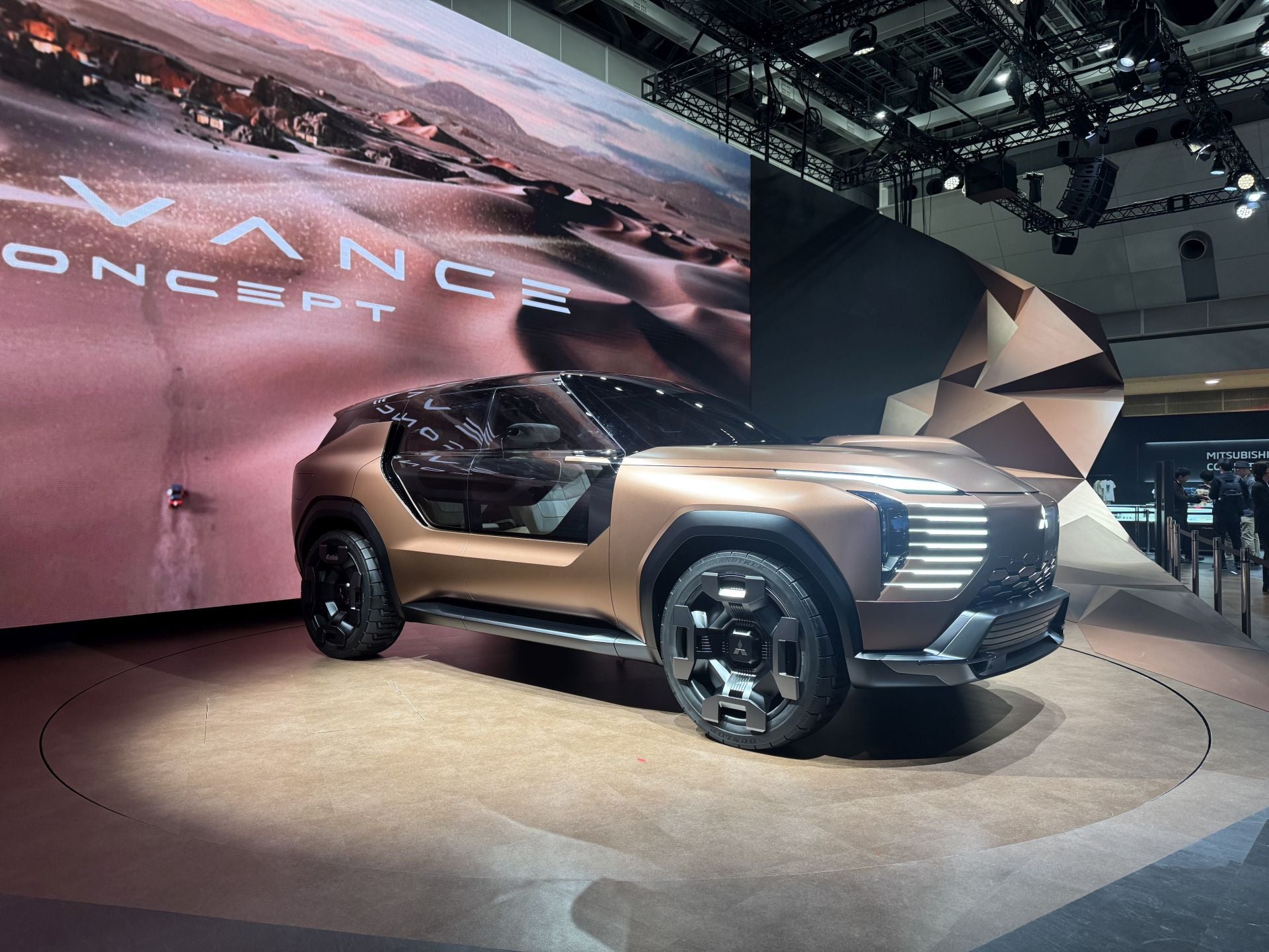 La marca japonesa Mitsubishi Motors aprovechó el JMS 2025 para presentar su visión de movilidad centrada en la aventura, con nuevos conceptos, modelos kei-car y tecnologías híbridas. Presentó el Mitsubishi Elevance Concept, un crossover SUV electrificado de estreno mundial que combina el diseño urbano con capacidades de todoterreno y un interior pensado para una experiencia confortable de viaje («glamping»). También se mostró el All‑New Delica Mini, un «super height-wagon» kei-car (categoria microvehículo japonesa) que hereda el nombre Delica y que se perfila como un compañero urbano-activo, con cinco modos de conducción recién añadidos. Bajo el tema del stand «Forever Adventure», Mitsubishi configuró un entorno de exhibición inmersivo que simula un paisaje desértico, incluyendo efectos sensoriales y experiencias interactivas para conectar con el espíritu de la exploración.