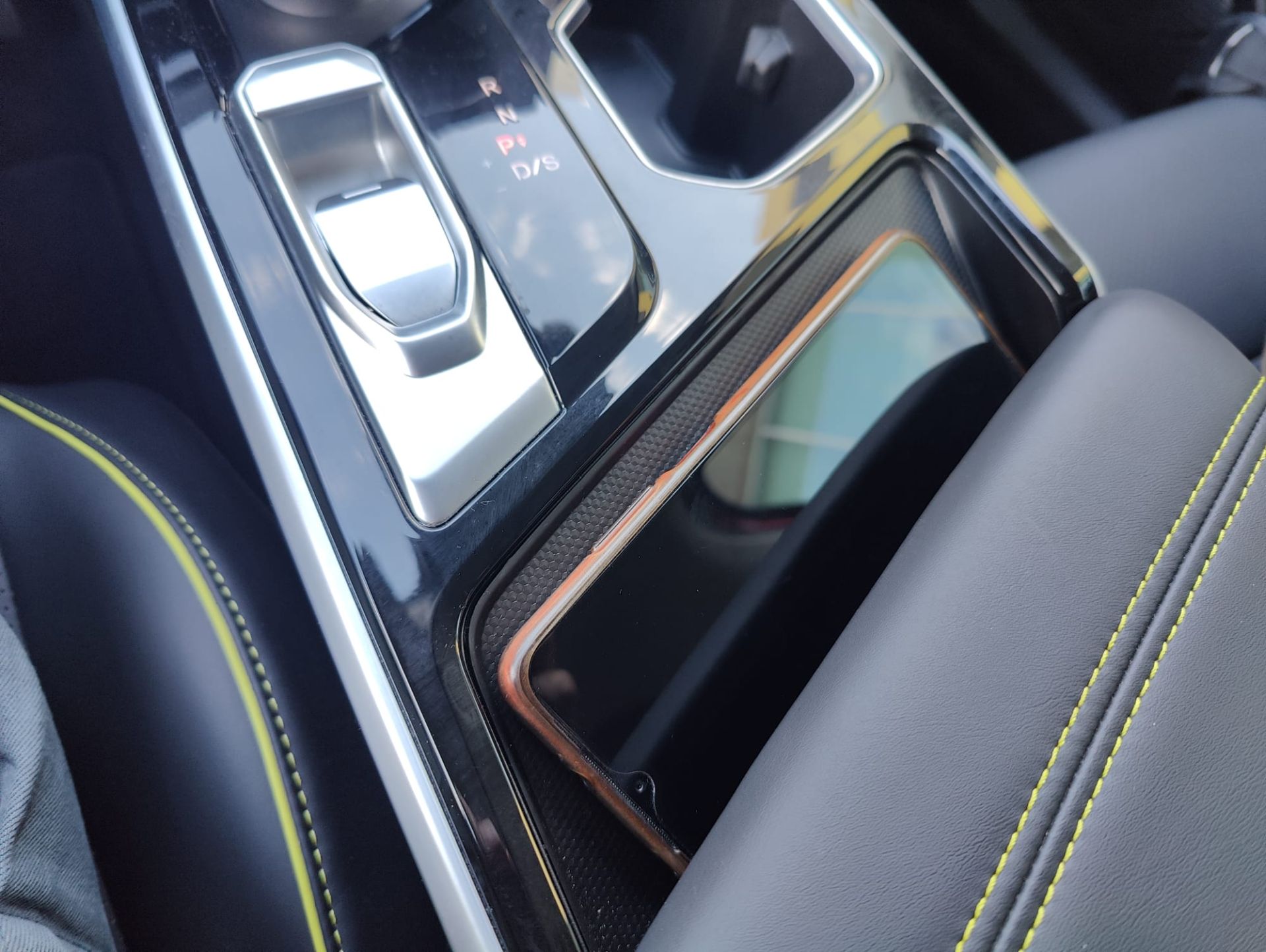 Para recargar el teléfono móvil en la consola central, justo por detrás de los portabotes, el BAIC X55 dispone de cargador inalámbrico. Esta función, como otras muchas en este modelo, se puede personalizar a través del menú «Conducción» de la pantalla central. De esta forma, si el móvil del conductor no soporta la función de recarga inalámbrica, puede desactivar esta superficie y dejarla como simple soporte del teléfono o destinarla para almacenar otros objetos.