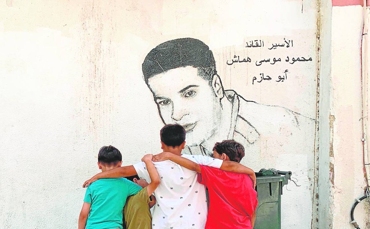 Varios niños miran un mural dedicado a Mahmoud Hammash, miembro de Fatah, considerada terrorista por Israel, que estuvo 14 años en prisión