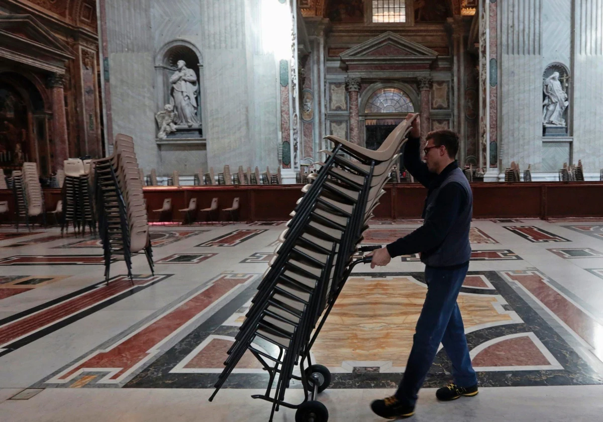 Un operario traslada sillas dentro de la Basílica de San Pedro, en el Vaticano