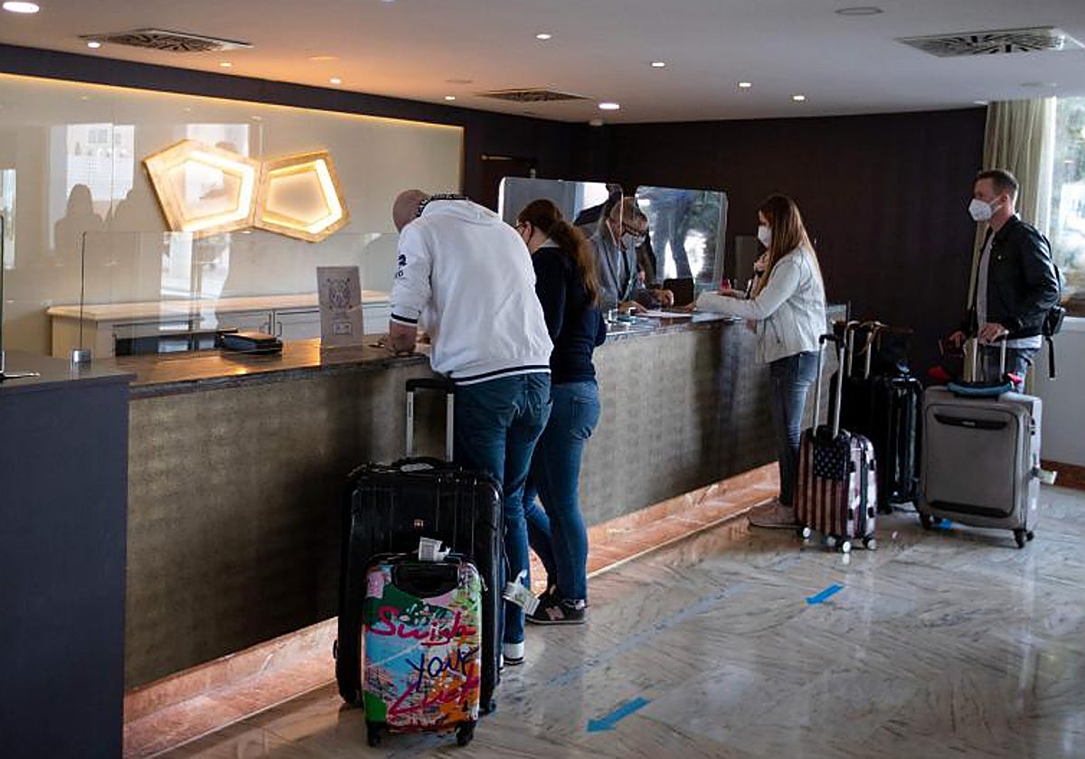 Dos personas tramitan su entrada en un hotel