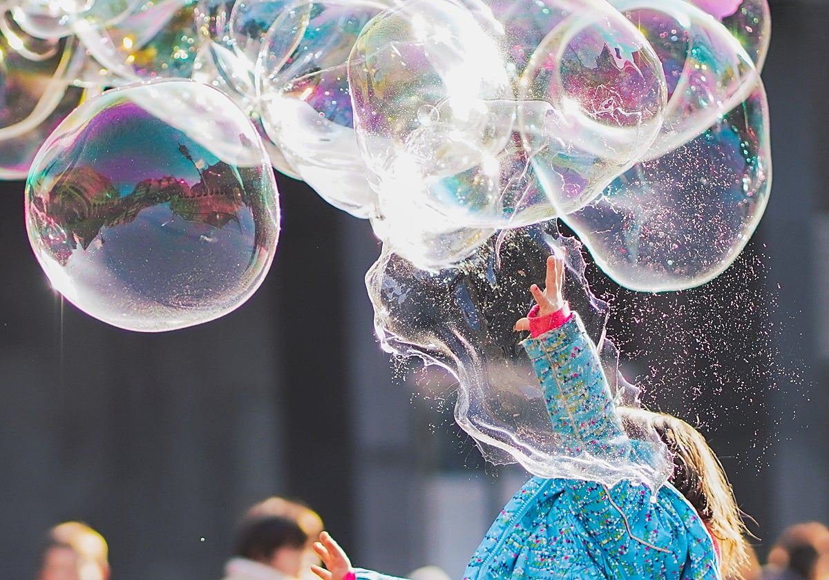 Una niña juega con pompas de jabón en una calle de la ciudad