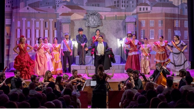 Elena Martínez Delgado dirigiendo a los músicos con los cantantes en el escenario en otra parte del espectáculo