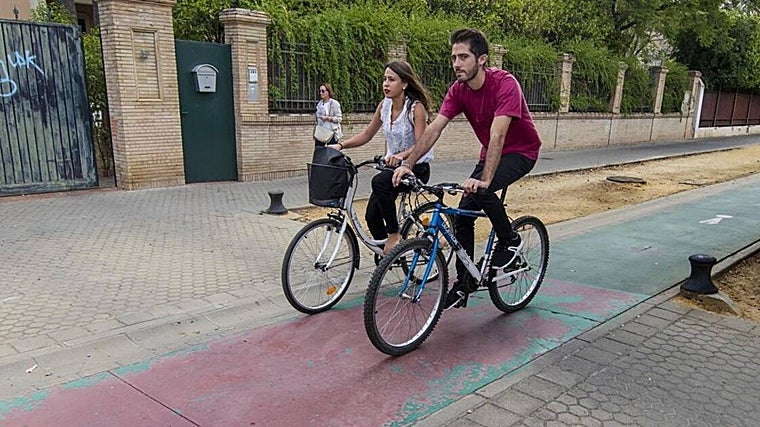 Dos personas recorren el carril bici de Sevilla en su tramo por la Avenida de la Palmera