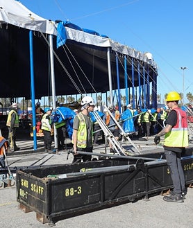 Segunda imagem 2. Trabalhadores montam uma grande tenda.