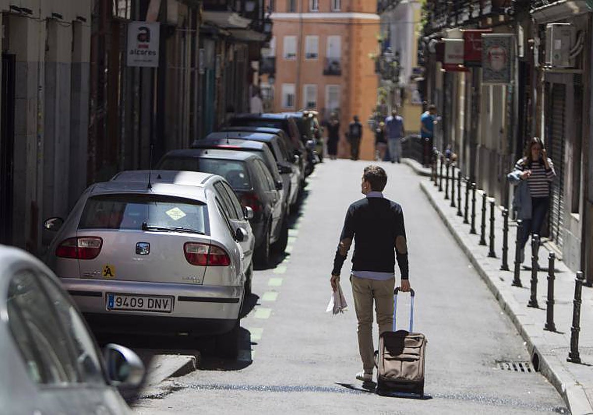 Un turista, con su maleta por un barrio de Madrid