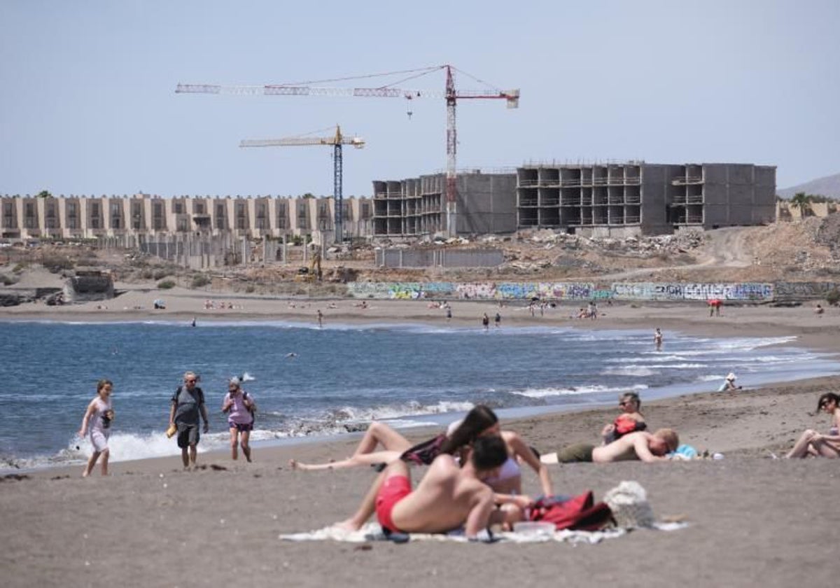 Turistas en la playa de La Tejita, en el sur de Tenerife, justo al lado de las obras de un nuevo hotel