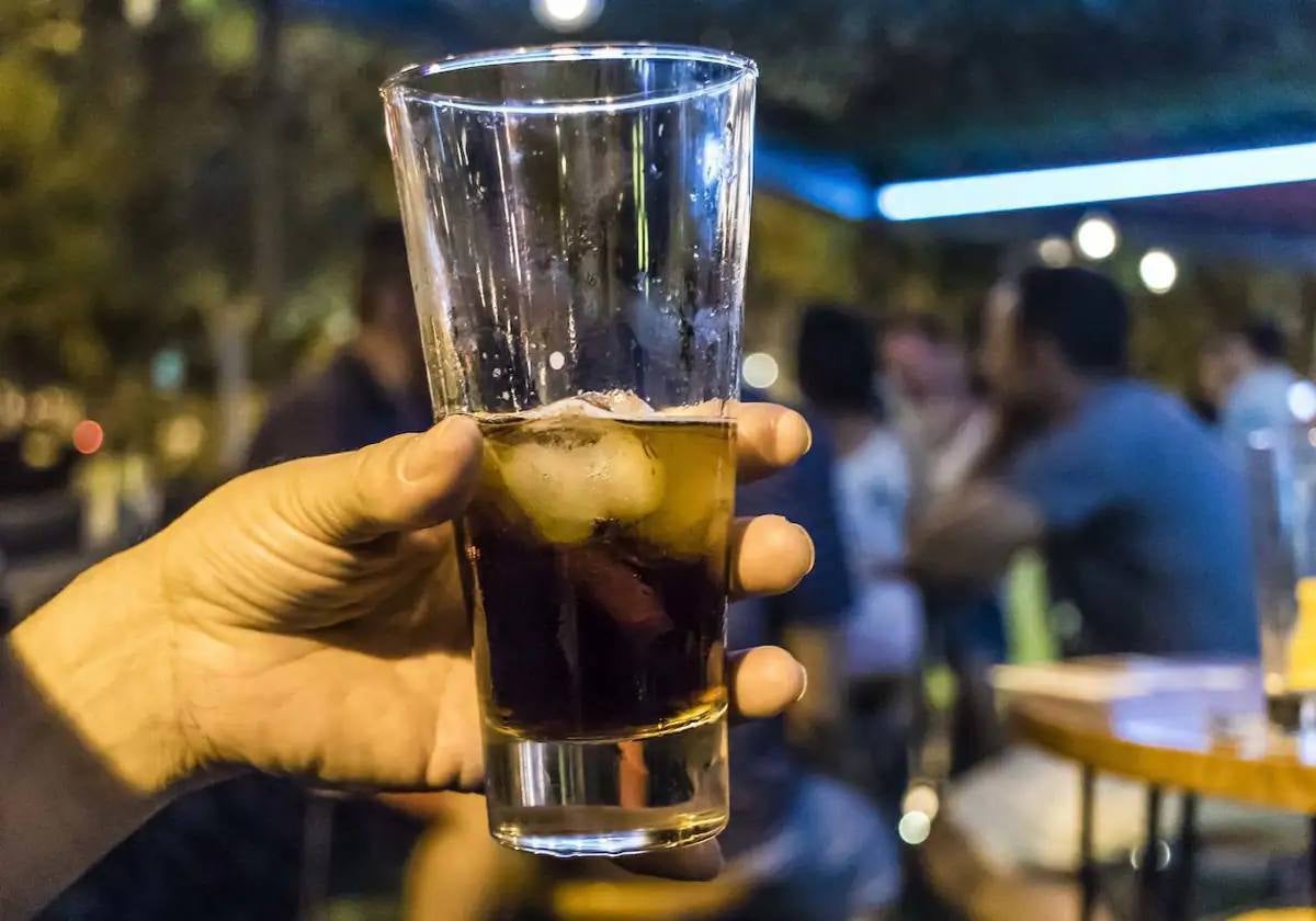 Una persona sostiene una bebida alcohólica