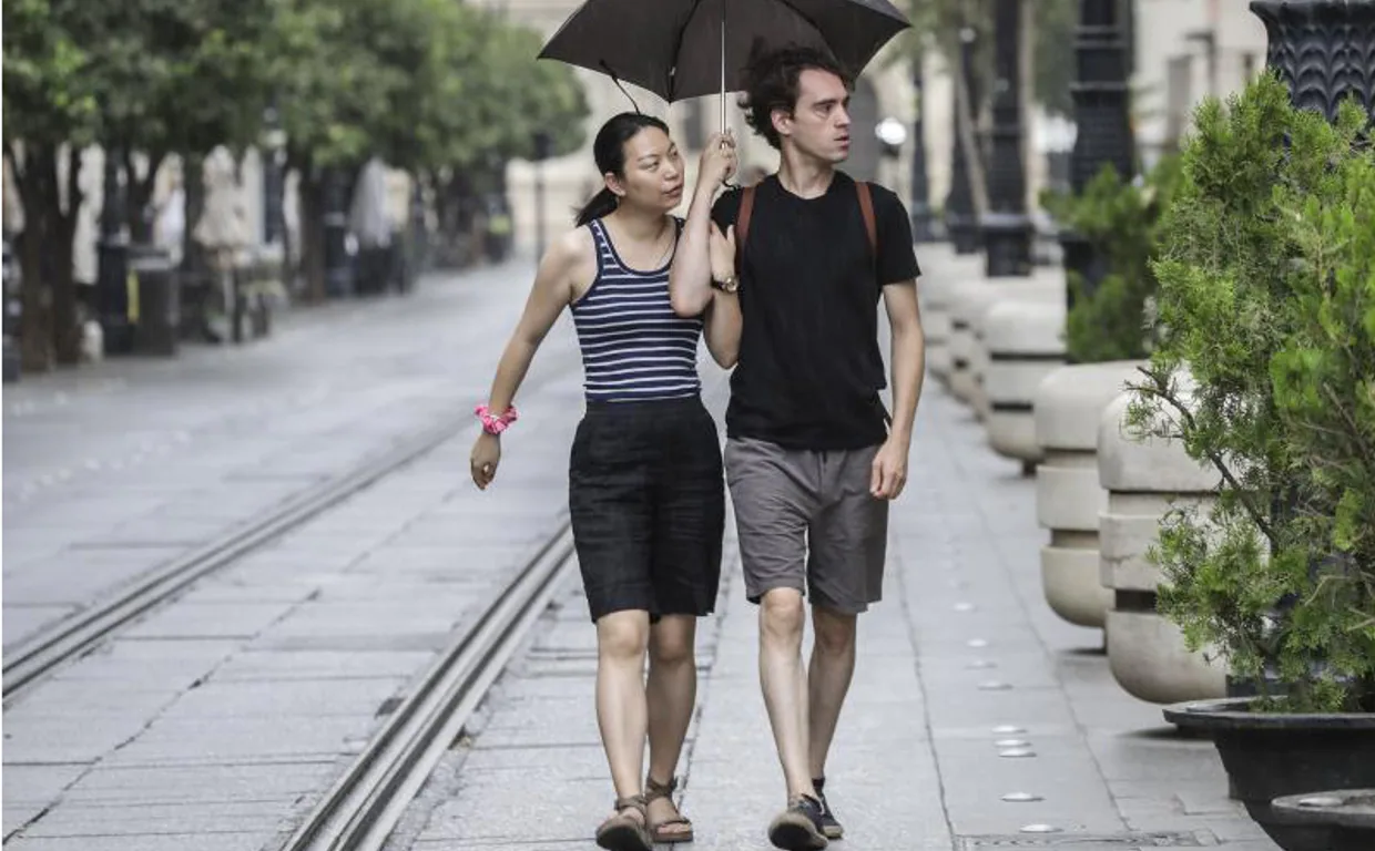 Dos turistas sorprendidos este sábado por la lluvia en la avenida de la Constitución