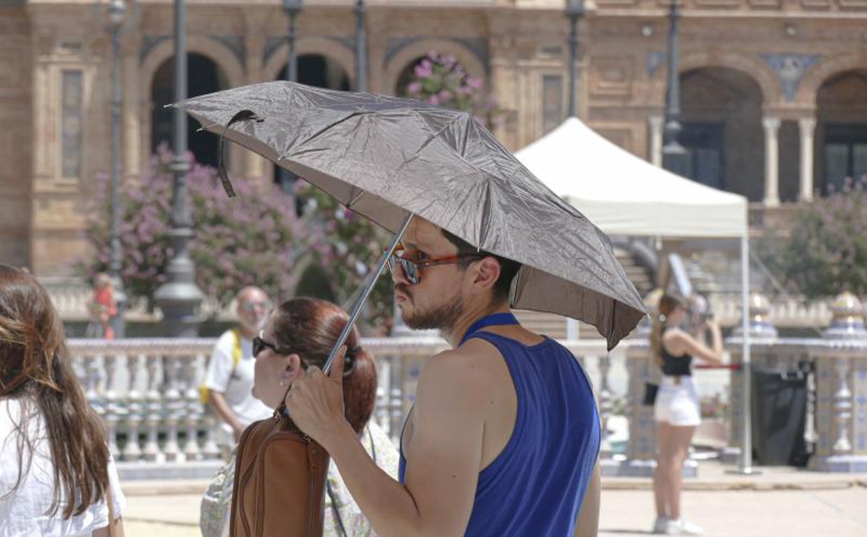 Varios turistas se protegen del sol este pasado mes de julio en la Plaza de España de Sevilla