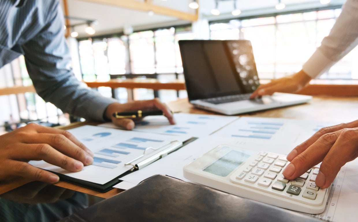 Dos personas realizan un análisis con gráficas y calculadora sobre la mesa de un despacho