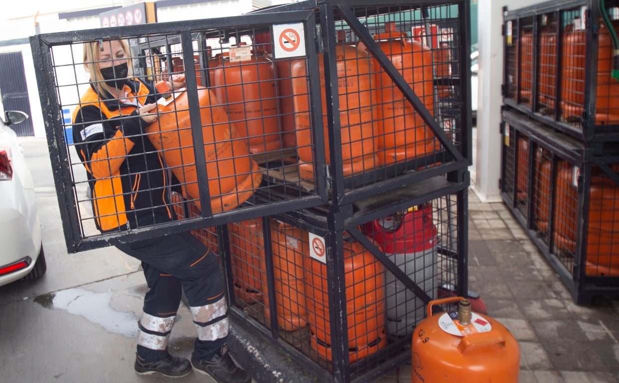 Una trabajadora de una gasolinera saca una bombona de butano