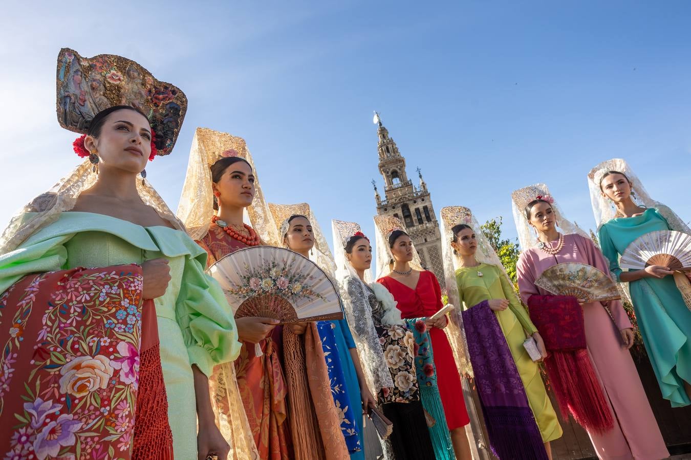 Unas jóvenes con mantilla blanca posan con la Giralda al fondo en la jornada de la Mantilla blanca