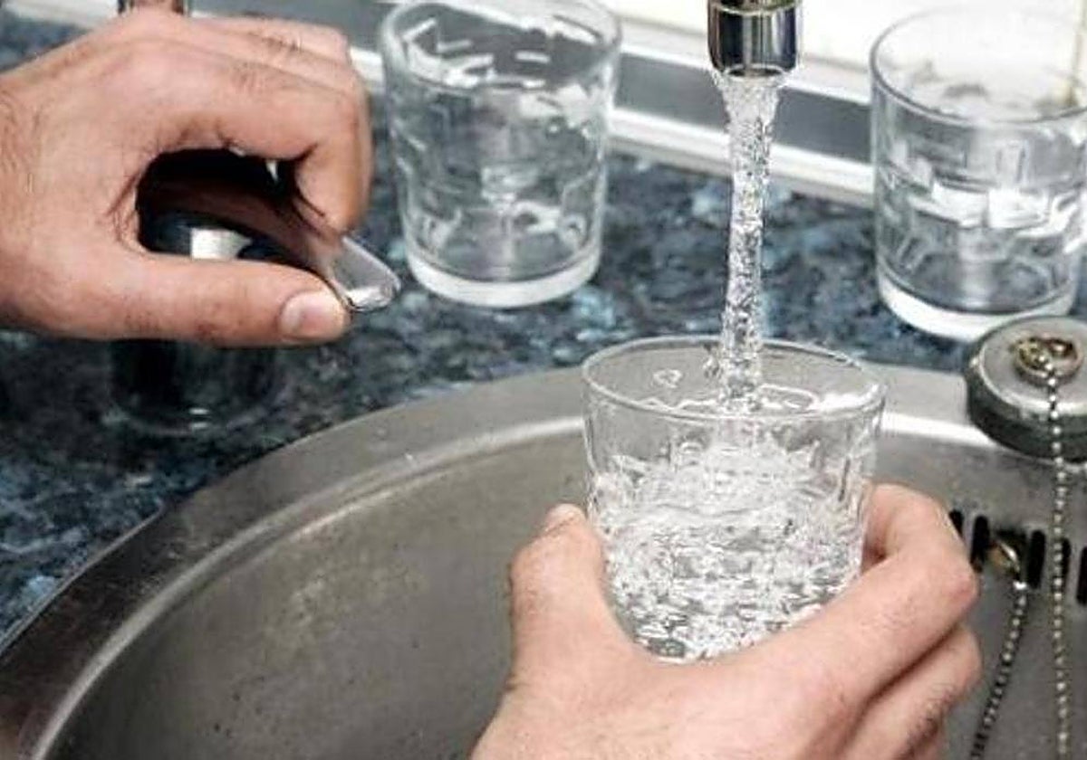 Una persona llena un vaso de agua de un grifo