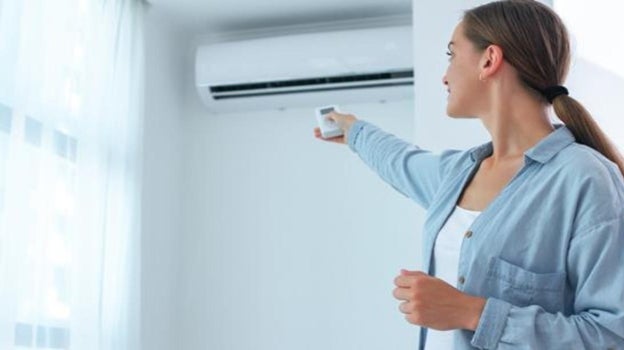 Imagen de una mujer encendiendo un aire acondicionado
